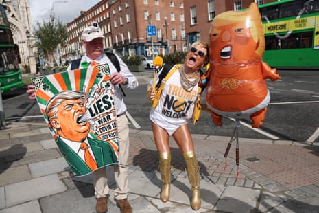 A man with orange fake tan holding a Trump baby balloon.