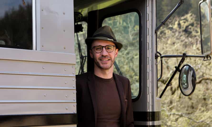 Man wearing a hat standing at door of a vehicle.