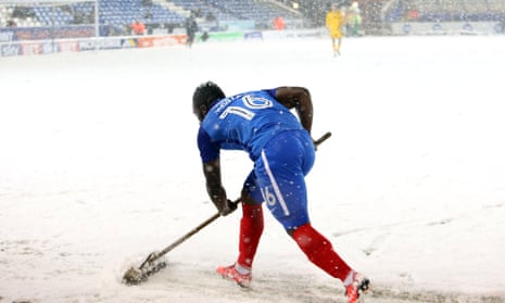 Junior Morias clears snow off the pitch during the match.