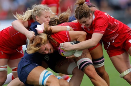Georgia Evans of Wales, wearing a pink ribbon in her hair, takes the ball into a multiple tackle after coming on as a substitute.