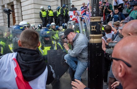 Riot police push a protester against a lamppost as other demonstrators look on
