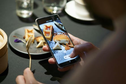 A diner takes a video of a meal featuring a nugget made from lab-grown chicken meat during a media presentation in Singapore.