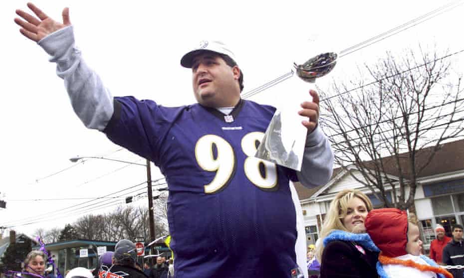 Tony Siragusa, defensive tackle for the Super Bowl-champion Baltimore Ravens, holds the Vince Lombardi trophy as he rides with his wife, Kathy, in a parade in his hometown of Kenilworth, New Jersey in March 2001