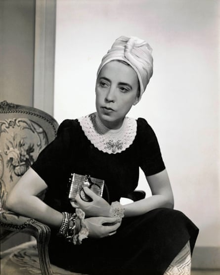 Elsa Schiaparelli sitting on a chair, wearing a white turban and a black dress