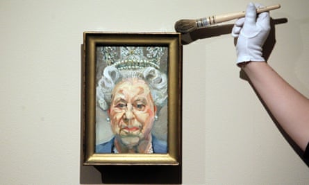 A curator dusts a portrait by Lucian Freud of Queen Elizabeth II as part of the exhibition The Queen: Portraits of a Monarch at Windsor Castle in 2012.