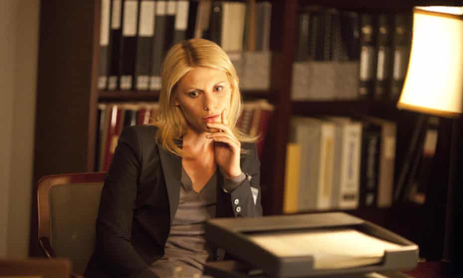 Claire Danes as Carrie Mathison in Homeland sitting and looking contemplative in a study surrounded by books and files