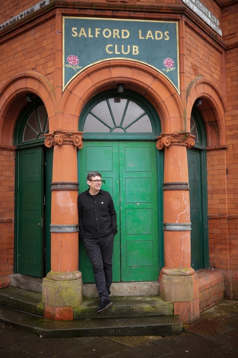 Andy Burnham stands before a green door beneath a sign reading 'Salford Lads Club'
