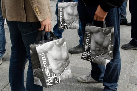 les gens tiennent des sacs abercrombie avec des hommes torse nu dessus