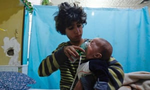 A Syrian boy holds an oxygen mask over the face of an infant at a makeshift hospital following a reported gas attack on the town of Douma in eastern Ghouta.