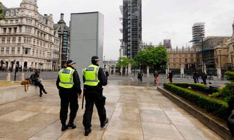 Police officers walk past a boarded-up statue of Winston Churchill on Parliament Square, London.