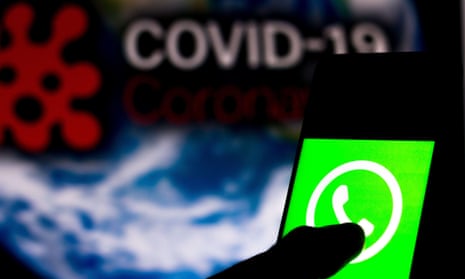 WhatsApp logo displayed on a smartphone with a computer model of the words 'Covid-19'  in the background