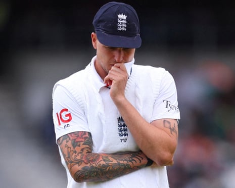 England's Brydon Carse stands with arms crossed, touching his chin thoughtfully during a Test match.