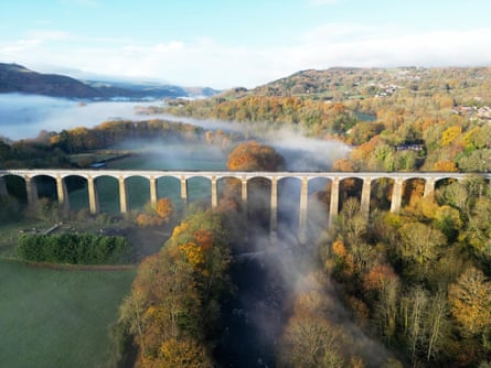 Overhead shot of a very tall aqueduct crossing water and autumnal woods