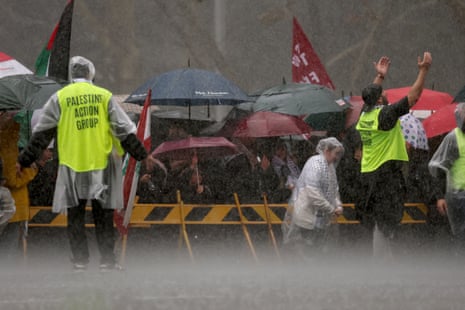 Demonstrators wait in the torrential rain as they prepare to cross the Sydney Harbour Bridge