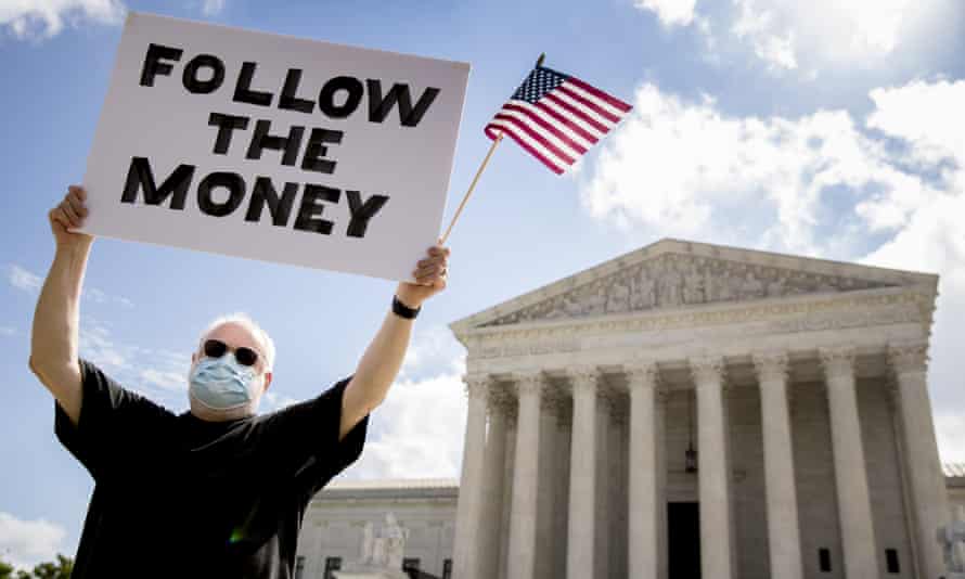 Bill Christeson holds up a sign that reads 'Follow the Money' outside the supreme court as it issued an initial ruling on the release of Donald Trump's tax returns last July.