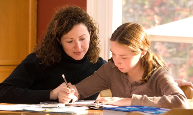 Mother helping her daughter with her home schooling homework in kitchen.