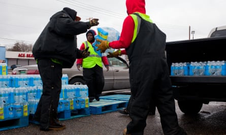 Workers load cars with cases of water in front of the closed bowling alley. Flint Michigan water supply crisis