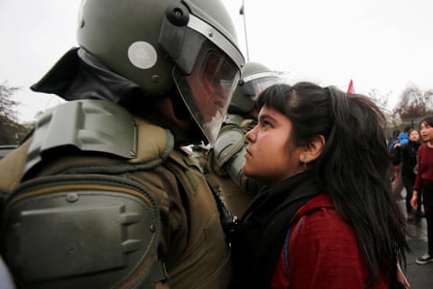 A demonstrator looks at a riot policeman during a protest marking the country's 1973 military coup in Santiago, Chile September 11, 2016.
