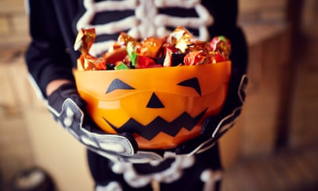 Boy in skeleton costume holding bowl full of candies