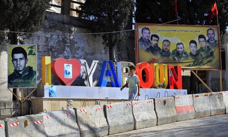 A youth walks past a sign in Yaroun, south Lebanon
