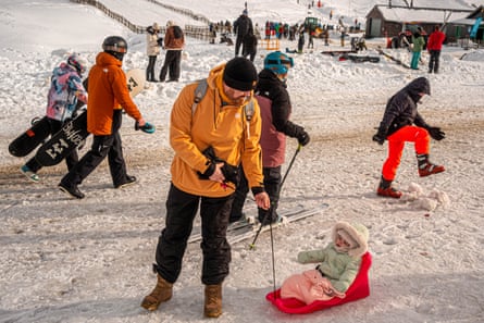 Tiny child being pulled on small red sled