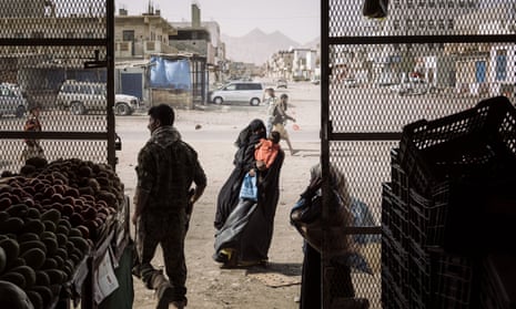 A woman begs outside a grocery store in the town of Azzan, Yemen