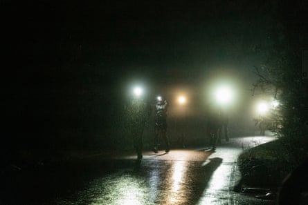 Runners wearing headlamps run through the rain