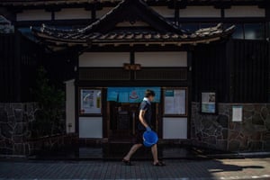 A staff member walking past the entrance of the Kanamachi sento