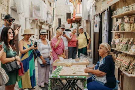 Tourists watch Nunzia Caputo make pasta outside her house