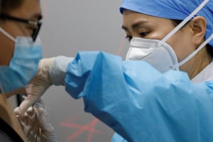 A medical worker prepares to administer a dose of a coronavirus vaccine to a man in Beijing.