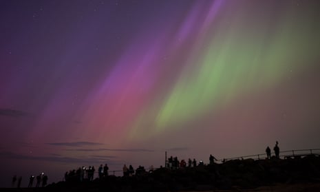Expanse of purple and green sky with silhouettes of people in the lower foreground