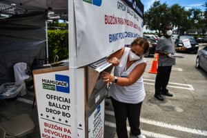 Poll workers help a voter put their mail-in ballot in an official Miami-Dade County drive-thru ballot drop box in Miami, Florida on 18 August.