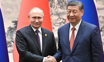 Vladimir Putin (L) and China's President Xi Jinping shake hands wearing navy suits, ties and white shirts