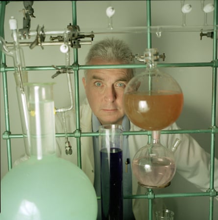 Robin McKie, in a scientist’s lab coat, peers through test tubes of liquid held up by metal rods