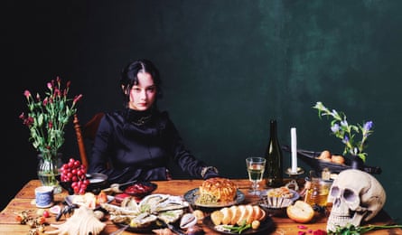 Japanese Breakfast’s lead singer, Michelle Zauner, sitting at a table laden with food, flowers and a skull.
