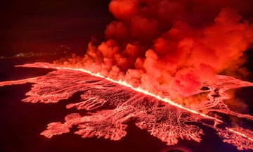 Billowing smoke and flowing lava pour out of an erupting volcano on the outskirts of Grindavik.