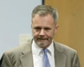 A middle-aged man with a beard and a tan suit, white shirt and blue tie.