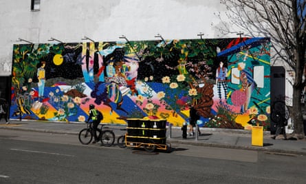 An Amazon delivery man rides past a street mural in the Bowery neighborhood of New York City.