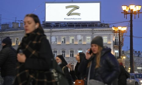 People walk past the letter Z,  a symbol of the Russian military, and a hashtag reading ‘We don't abandon our own’ in St Petersburg on 9 March.