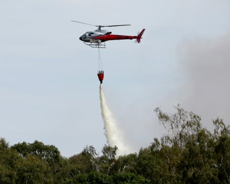 A helicopter drops water from a hanging bucket to fight a fire near Peterborough