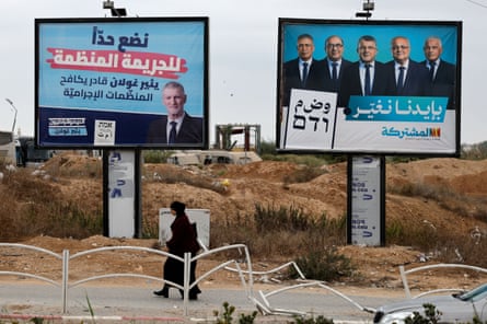 A Bedouin woman walks past election billboards for Yair Golan and Joint List leaders