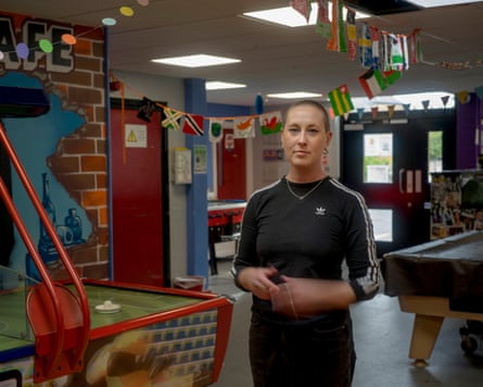 A woman stands at a pool and air hockey tables at a youth center