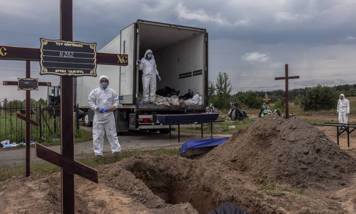Workers place bodies in coffins of unidentified people killed in Bucha district during a mass burial at a cemetery in Bucha, northwest of Kiev, Ukraine.