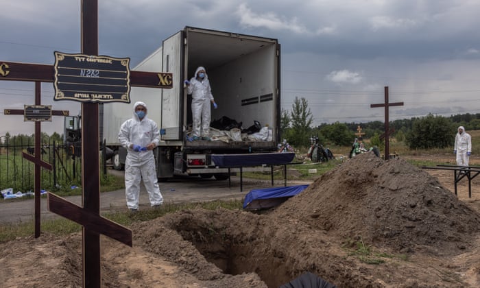 Workers place mortal remains in coffins of unidentified persons killed in the Bucha district during a mass burial at a cemetery in Bucha, northwest of Kyiv, Ukraine.