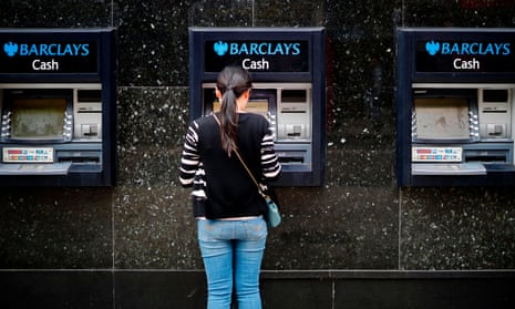 A woman withdraws cash from a Barclays cash machine