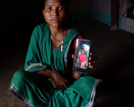 A woman holding a phone showing an image of a child.