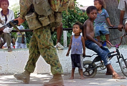 An Australian soldier on a foot patrol walks past East Timorese children in Dili in September 1999.