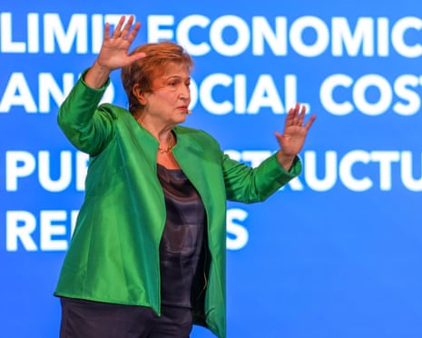 IMF chief Kristalina Georgieva raises both hands while speaking on stage before a blue screen