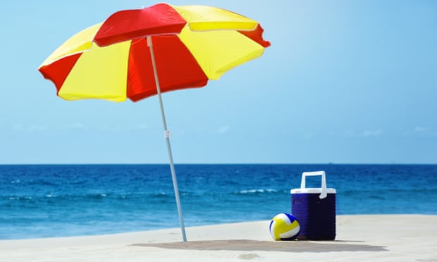 An umbrella and accessories on a beach with the sea in the background