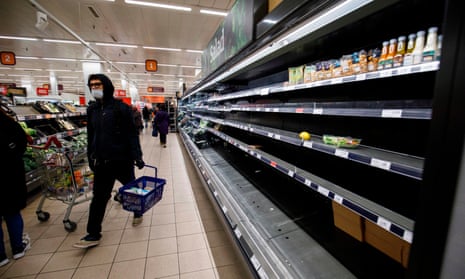 People shop in aisles with empty shelves in a Sainsbury’s supermarket in east London in March